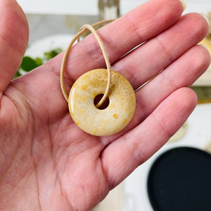 Versteinerte Koralle Donut, 30 x 30 x 6 mm, am Lederband