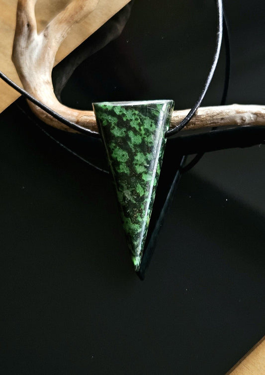 Dieser wunderschöne  Jadestein aus Italien besticht durch seine tannengrüne und schwarze Farbe. Er ist zu einem langgezogenen Dreieck sauber geschliffen und poliert, gebohrt , an hängt an einem verstellbarem schwarzem Lederband.