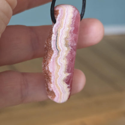 Wilder Rhodochrosit Anhänger mit einzigartiger Bänderung, 48 x 18 x 9 mm, an Lederband, high quality polish, heart chakra, self love