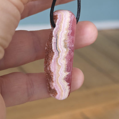 Wilder Rhodochrosit Anhänger mit einzigartiger Bänderung, 48 x 18 x 9 mm, an Lederband, high quality polish, heart chakra, self love